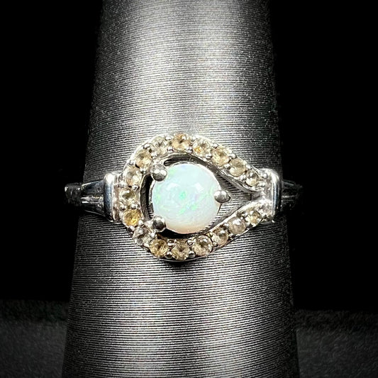Close-up front view of round Australian white opal women's ring with smoky quartz halo design in sterling silver, shown on ring display