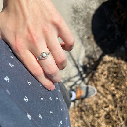 Close-up of person resting hand on hip in sunlight wearing a sterling silver round Australian opal and smoky quartz women's ring