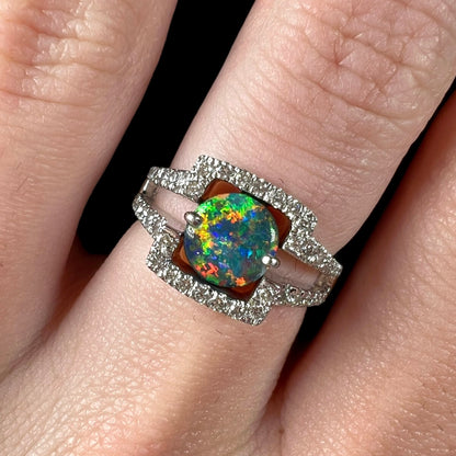 A square-shaped white gold and diamond-accented engagement ring set with a round black opal.