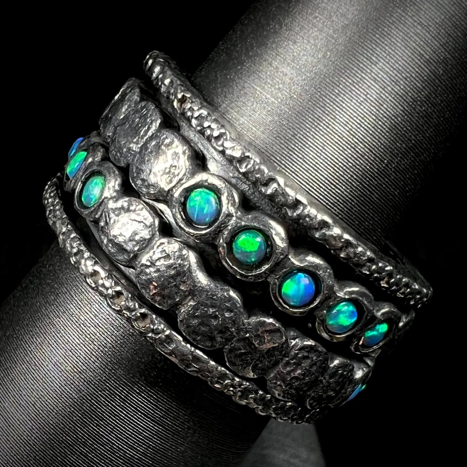 Side view of round opals with green color play, mounted into a silver spinner ring for men.