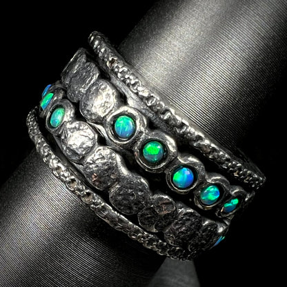 Side view of round opals with green color play, mounted into a silver spinner ring for men.