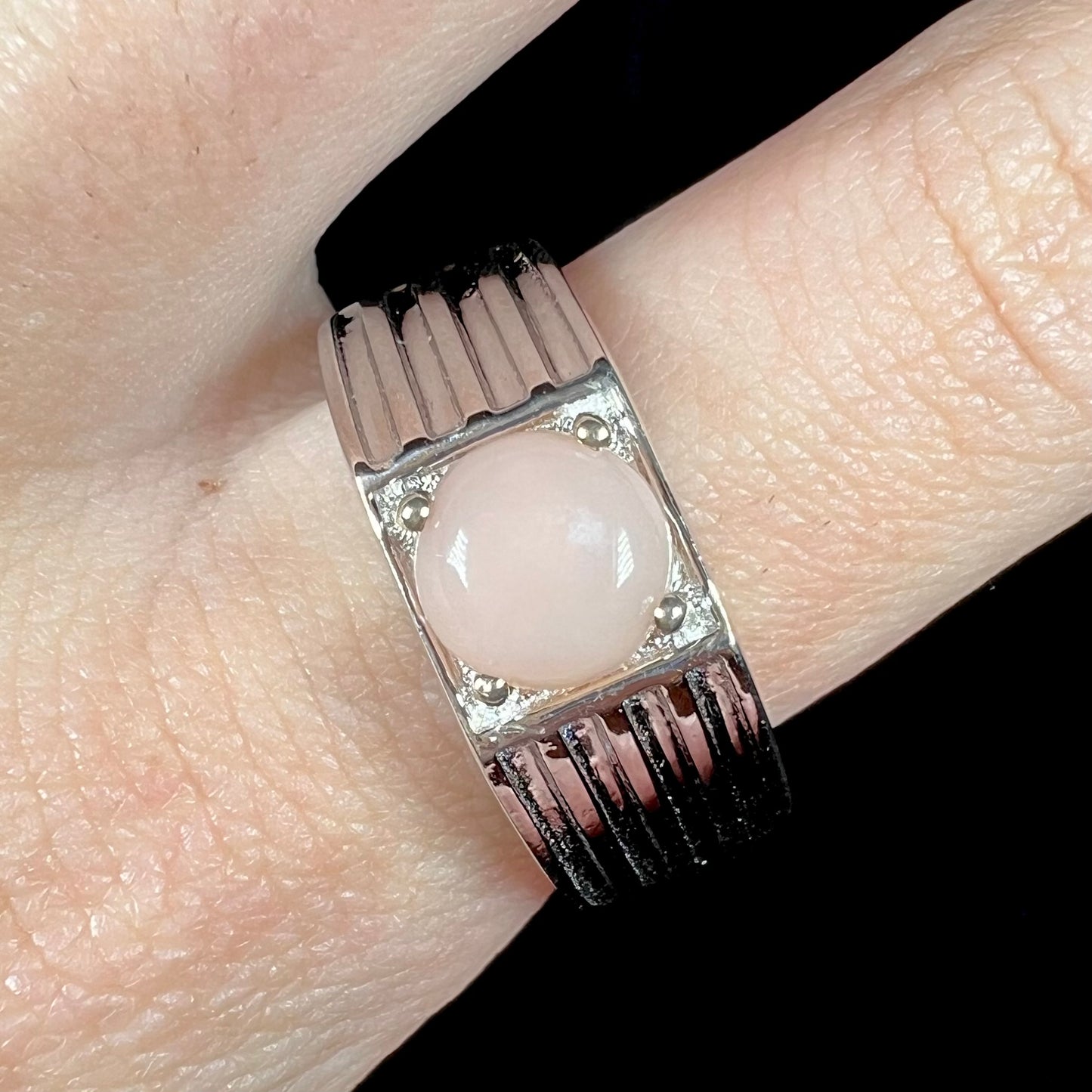 Close-up of sterling silver round pink Pervian opal ring on finger