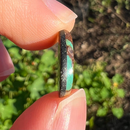 A freeform pear shaped Royston turquoise stone.  The stone is predominantly brown matrix with green turquoise around the edges.