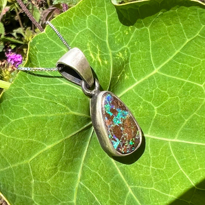 A handmade, satin finish sterling silver pendant set with a drop shaped boulder opal stone.