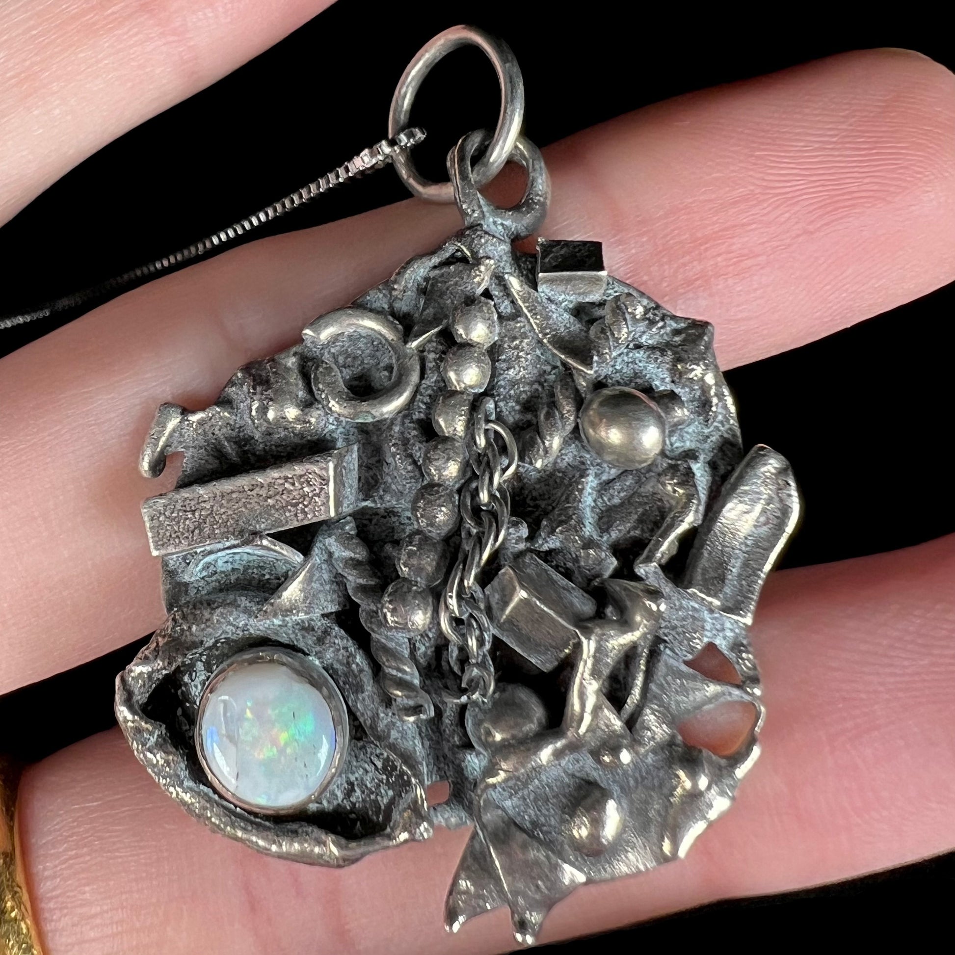 A scrap silver opal shipwreck necklace shown close-up from the front view.