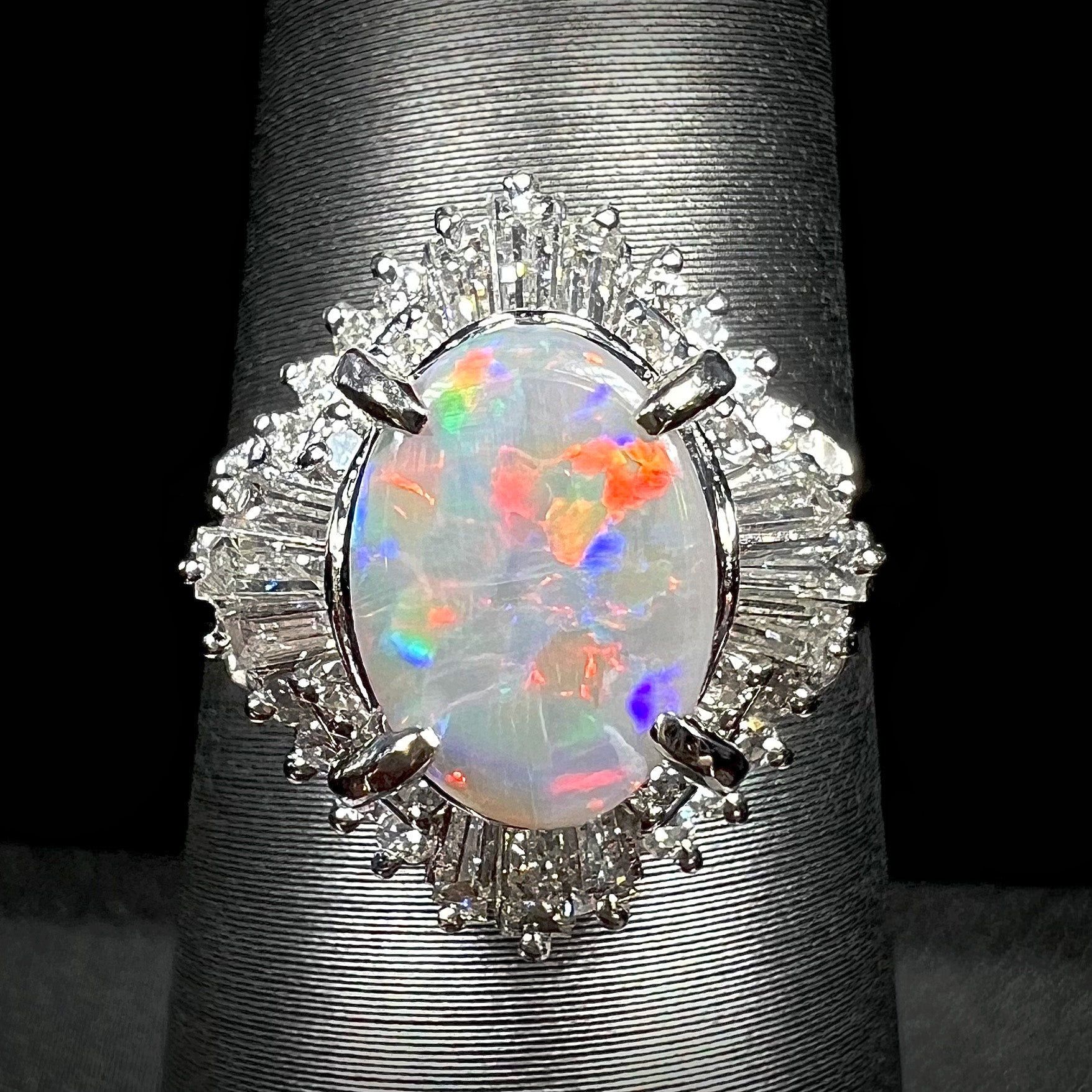 A vintage platinum semi-black opal and diamond ring with red and blue fire, featuring a Lightning Ridge opal surrounded by a diamond spray design.