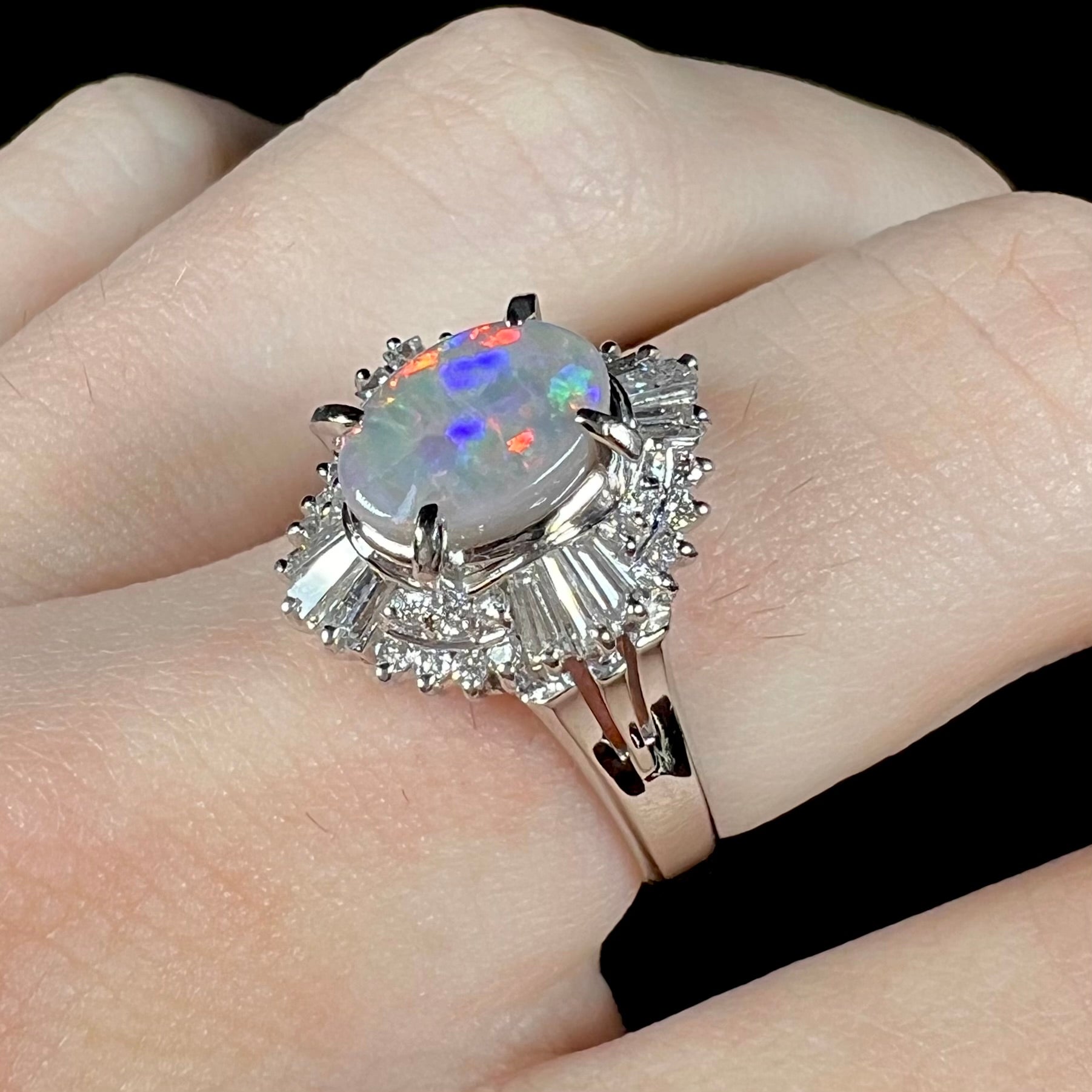 Macro view of a platinum semi-black opal and diamond ring, featuring a spray of diamonds set with round brilliant cuts and tapered baguettes.