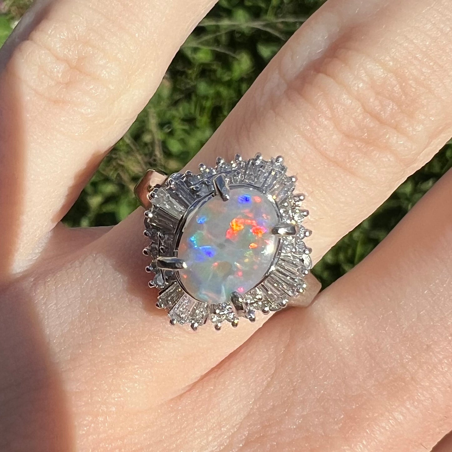 A semi-black opal engagement ring cast in platinum.  Surrounding the opal is a halo of round cut and baguette diamonds.