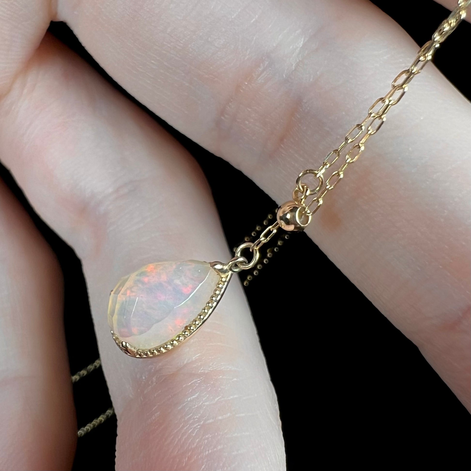 Side view of the opal necklace at an angle, showing very faint red flashes and the faceted surface.