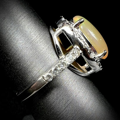 Side profile view of a sterling silver Ethiopian fire opal ring with a CZ halo.