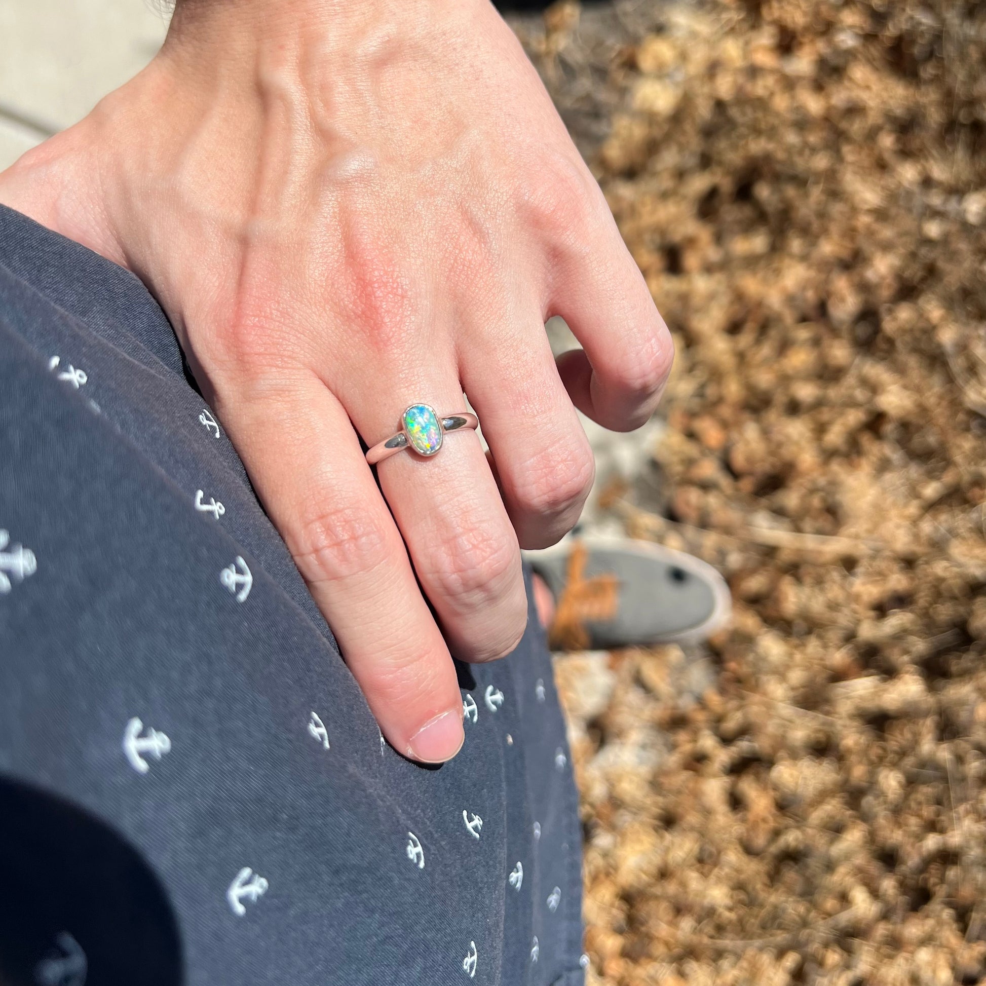 Hand resting on person's hip wearing silver Australian crystal opal ring in sunlight