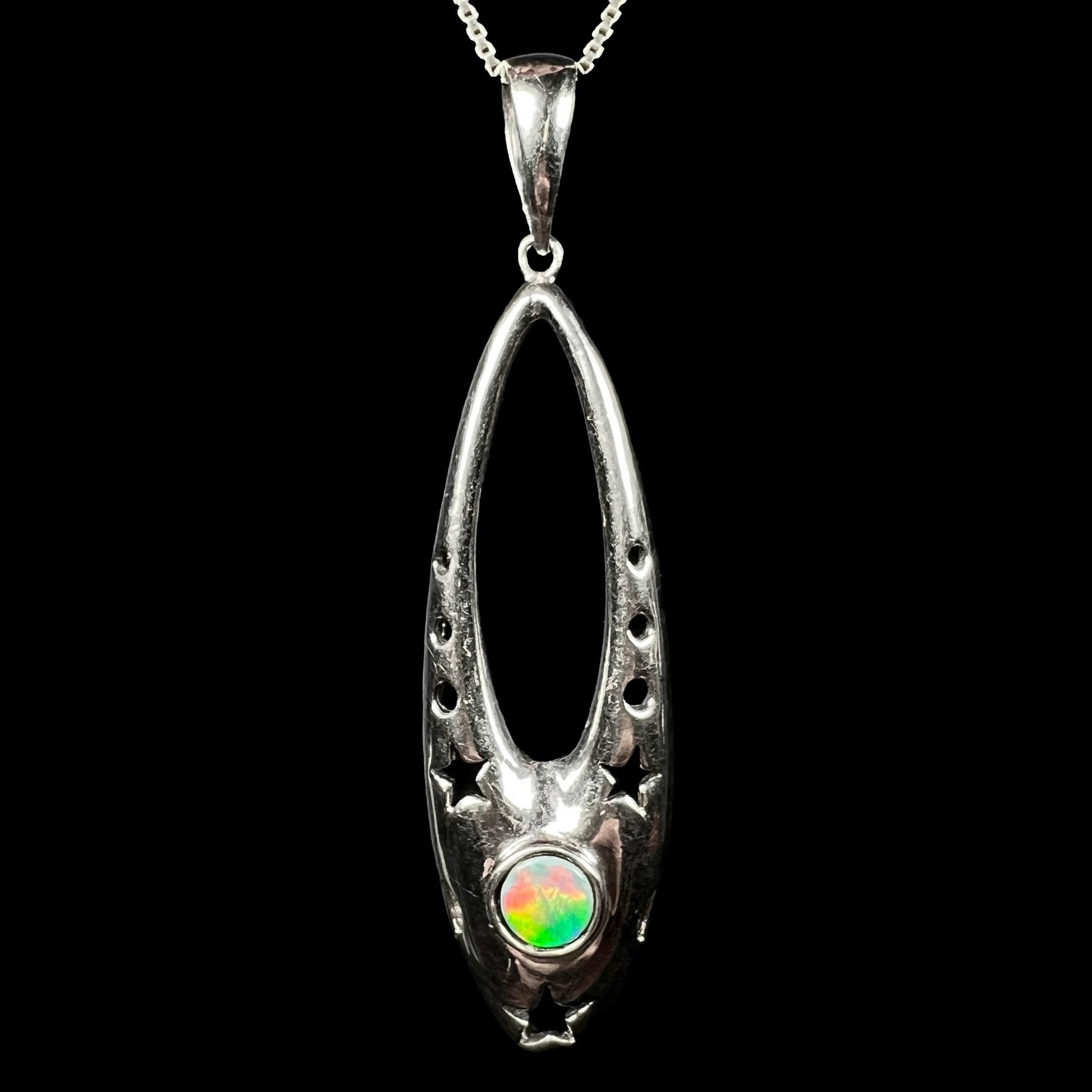 Close-up of a sterling silver ballerina shoe pendant with a colorful opal doublet, shown against black.