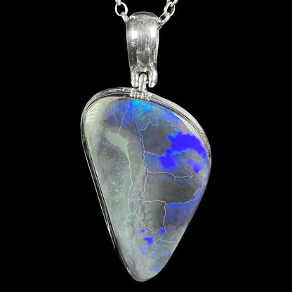 Close-up of a unisex sterling silver black opal pendant with dark opal mottling and blue flashes, shown on chain