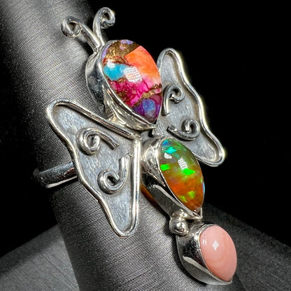A sterling silver butterfly ring set with different varieties of opals, shown at an angle.