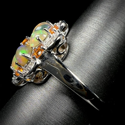Side view of a silver opal cluster ring against a black background.  A scratch can be seen in the ring's shank.