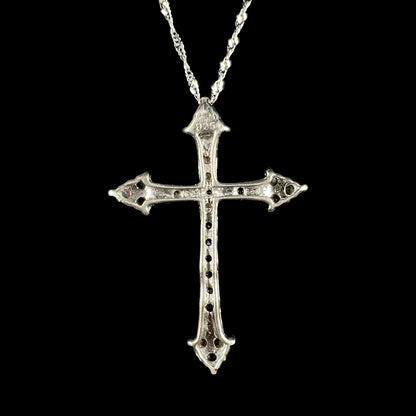 Back view of a silver cross necklace against a black backdrop.
