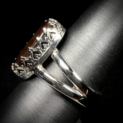 A sterling silver split shank ring with crown-design prongs shown from the side against dark backdrop.
