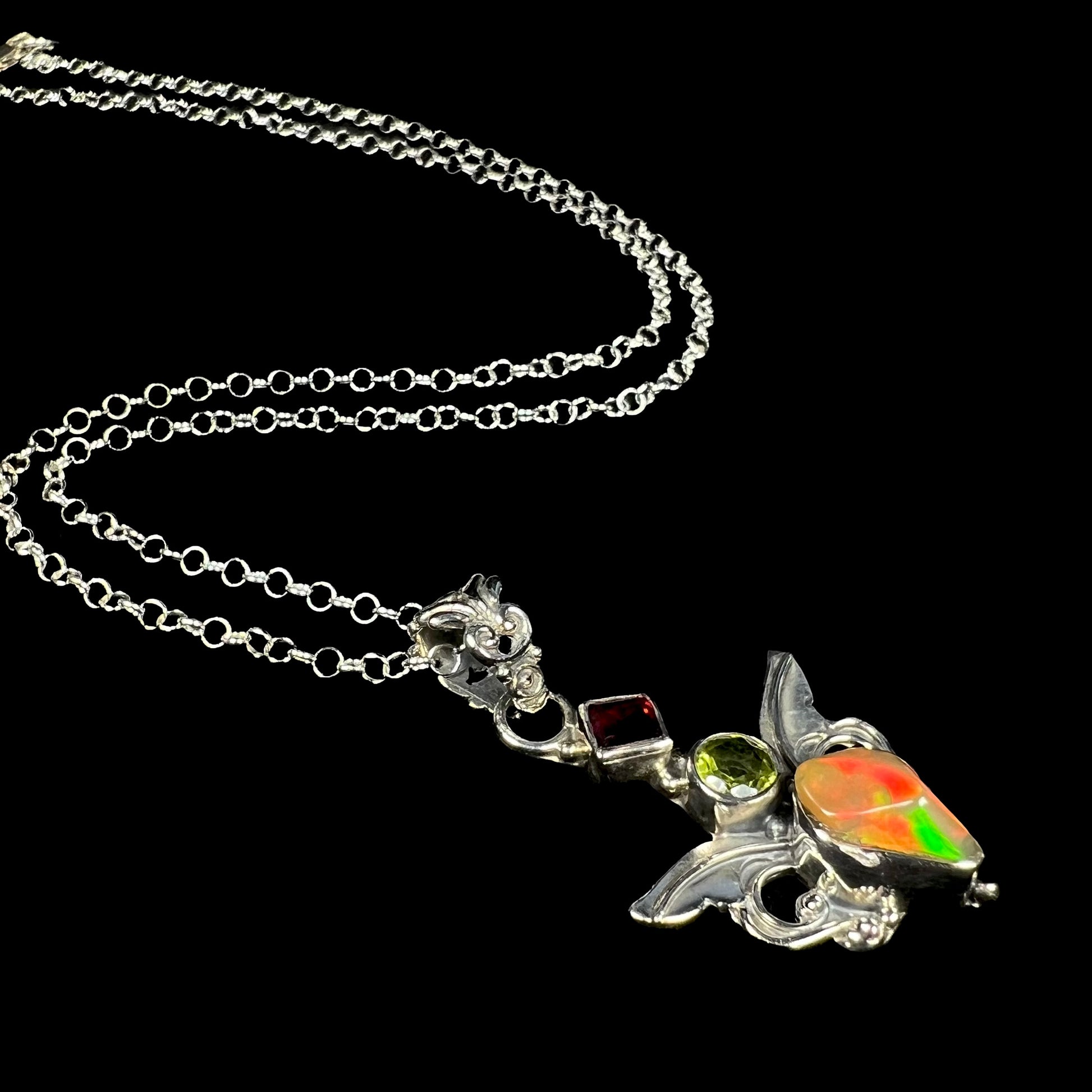 A sterling silver angel necklace set with an Ethiopian fire opal, peridot, and garnet.
