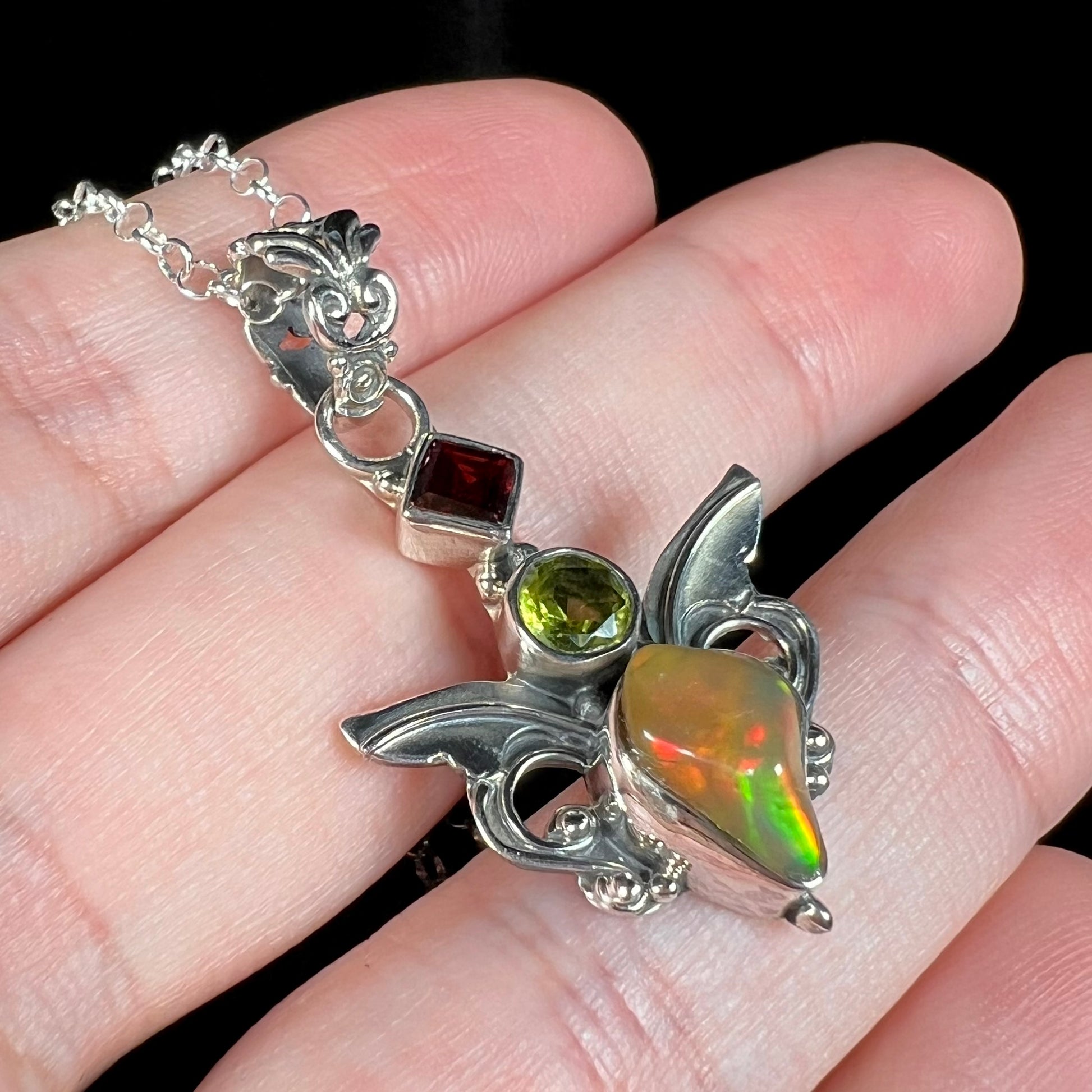 A sterling silver angel pendant set with an Ethiopian fire opal, peridot, and garnet.