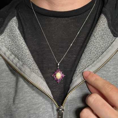 A sterling silver Ethiopian opal and rhodolite garnet spray necklace worn around a neck against a dark shirt.