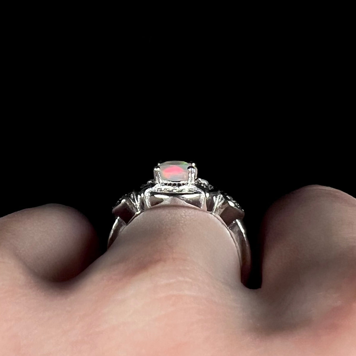 Side gallery profile view of sterling silver Ethiopian opal halo design ring, worn on finger