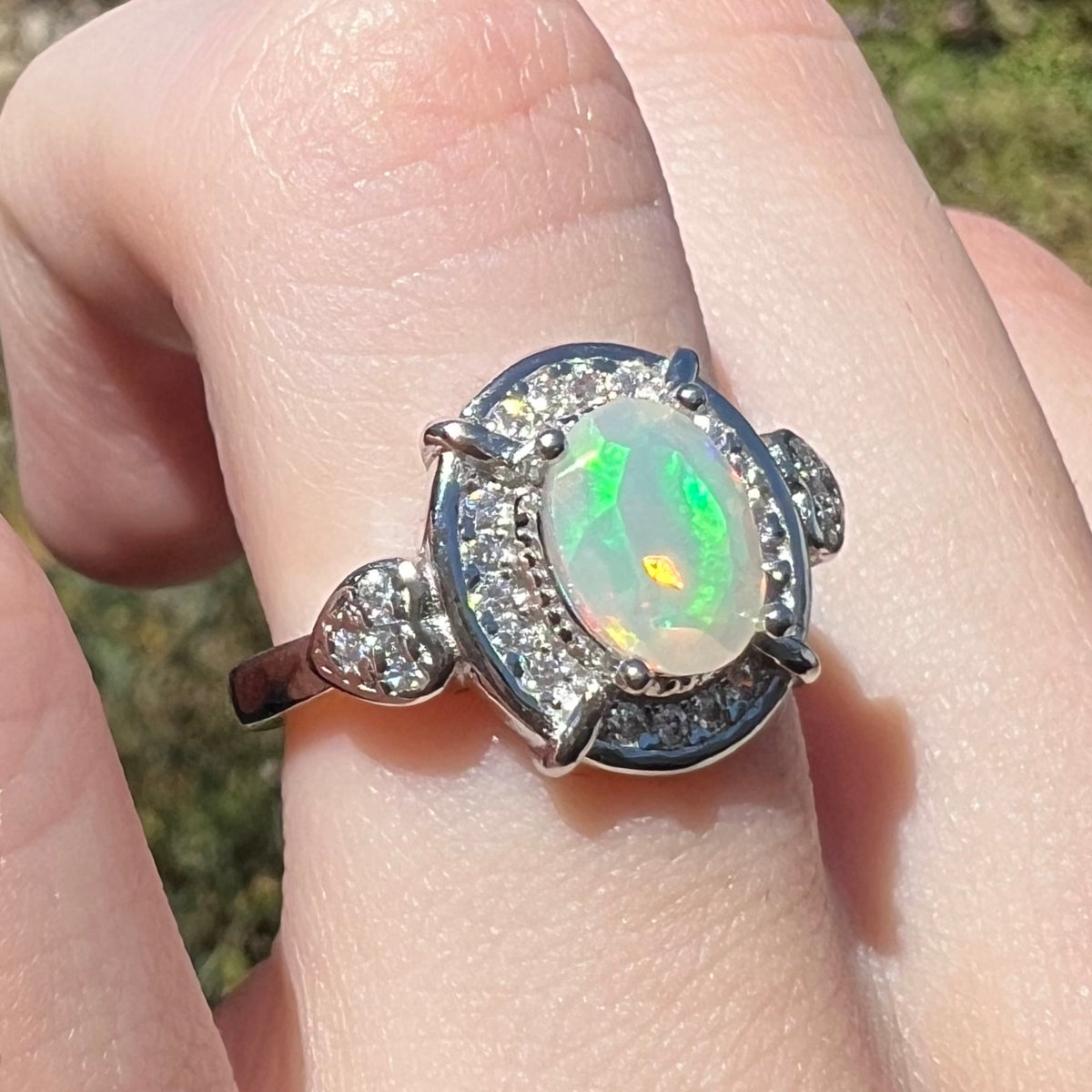 Sterling silver Ethiopian opal women's ring with green flashes of color, worn on finger in natural light