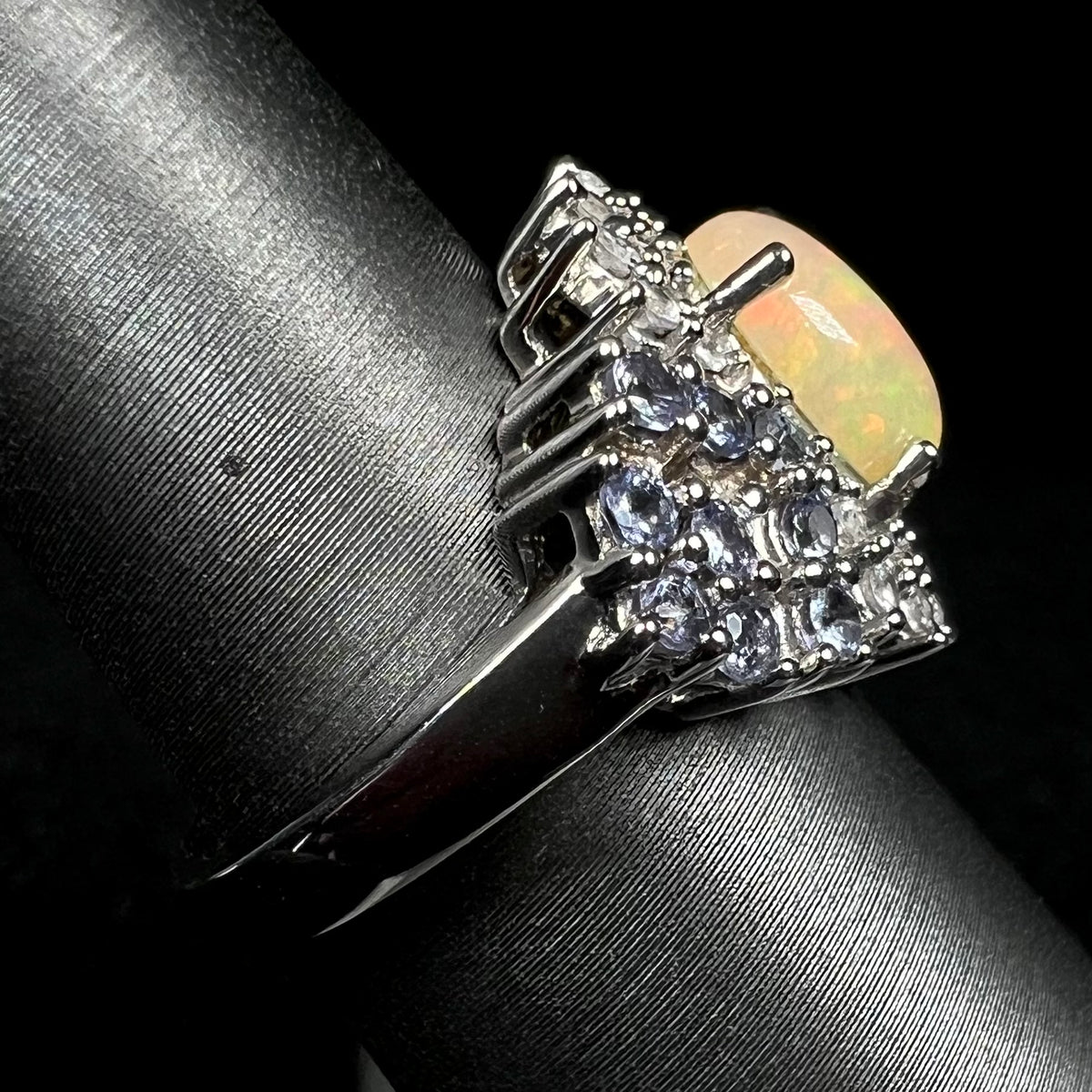 Sterling silver Ethiopian opal ring with tanzanite accents shown from the side view on ring display, focused on ring's shank