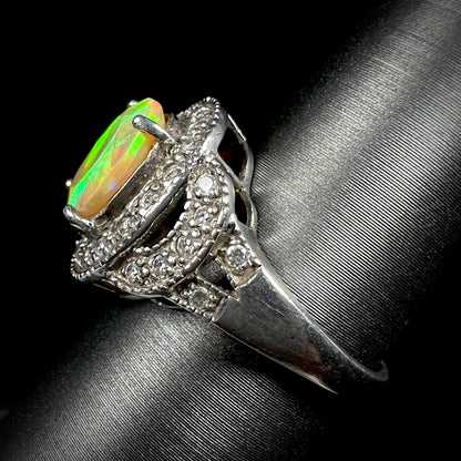 Side view of silver ring set with green Ethiopian opal and cubic zirconia accents against a black background.