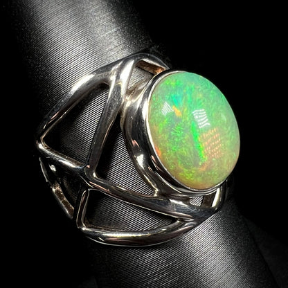 A sterling silver Ethiopian opal ring with green color play, shown at an angle against black background.