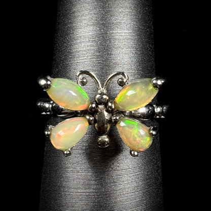 A sterling silver Ethiopian opal butterfly ring shown from the front on a ring display against a black background.