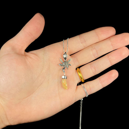 A sterling silver fairy necklace with an Ethiopian fire opal crystal, shown held in a hand against a black backdrop.