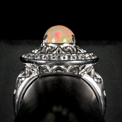 Side gallery of silver filigree opal statement ring against black background.