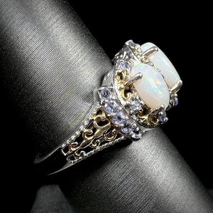 Side profile view of the gold-tone filigree on a sterling silver opal and tanzanite ring, shown on a ring display.