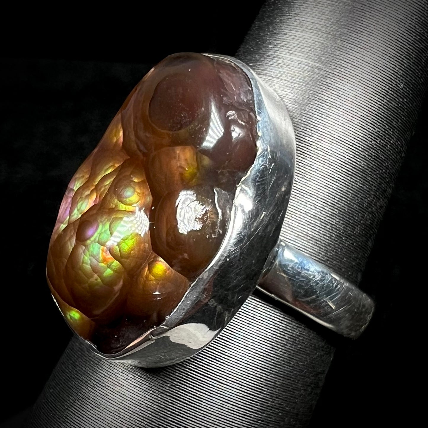 Angled view of a sterling silver Mexican fire agate ring with green and purple iridescence.