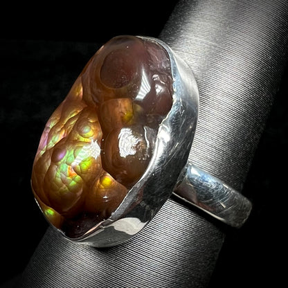 Angled view of a sterling silver Mexican fire agate ring with green and purple iridescence.