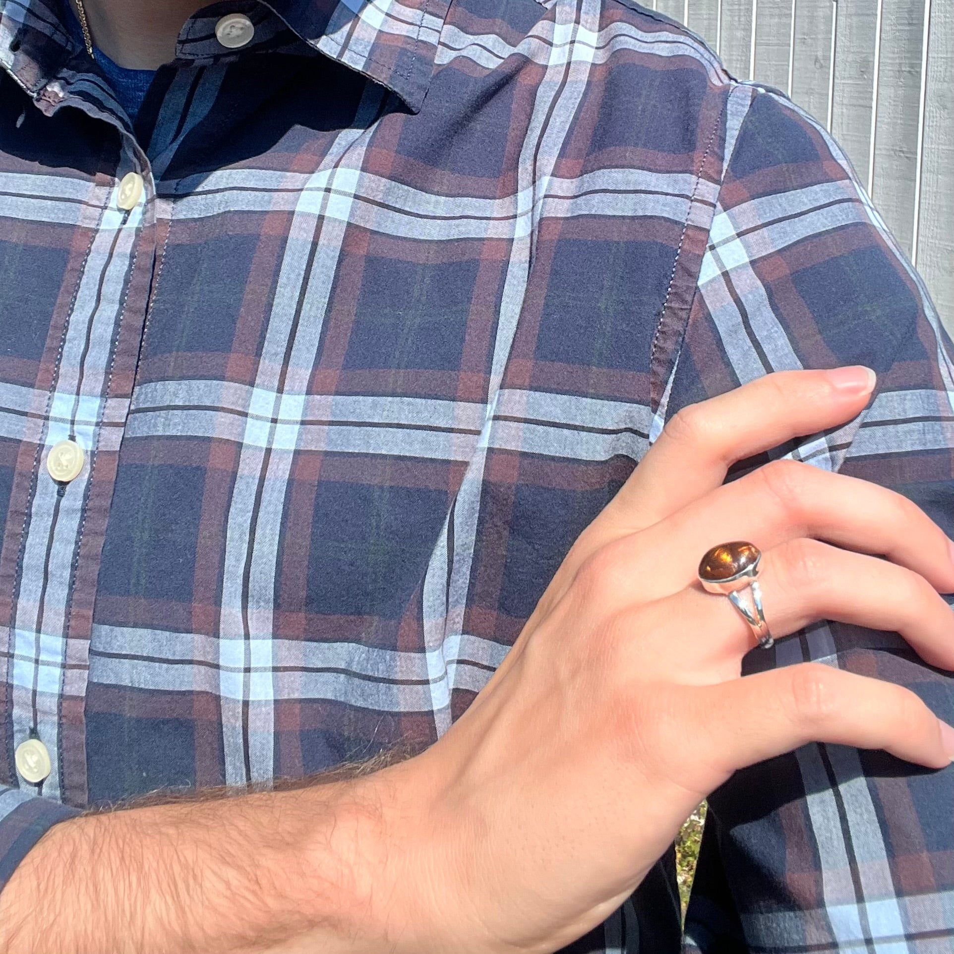 A sterling silver Mexican fire agate ring with a split shank worn on a model's hand that's resting on his shoulder.