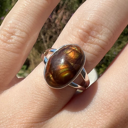 Close-up front view of a sterling silver Mexican fire agate ring with a split shank in the sunlight.