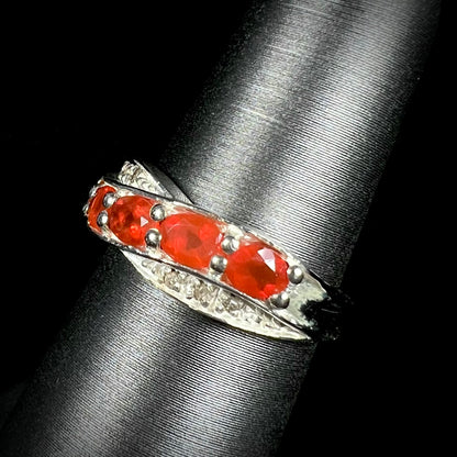 Angled view of orange Mexican fire opal ring in sterling silver against a black background.
