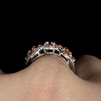 Side profile gallery view of a sterling silver fire opal ring on a hand.