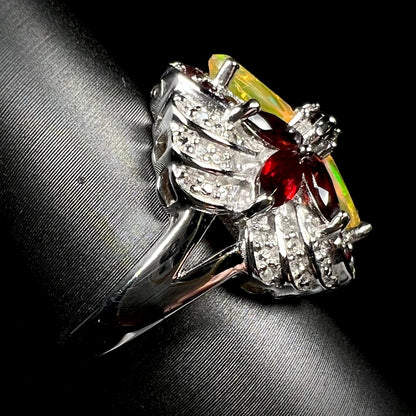 A silver garnet and opal ring with diamond accents, shown from the side view.