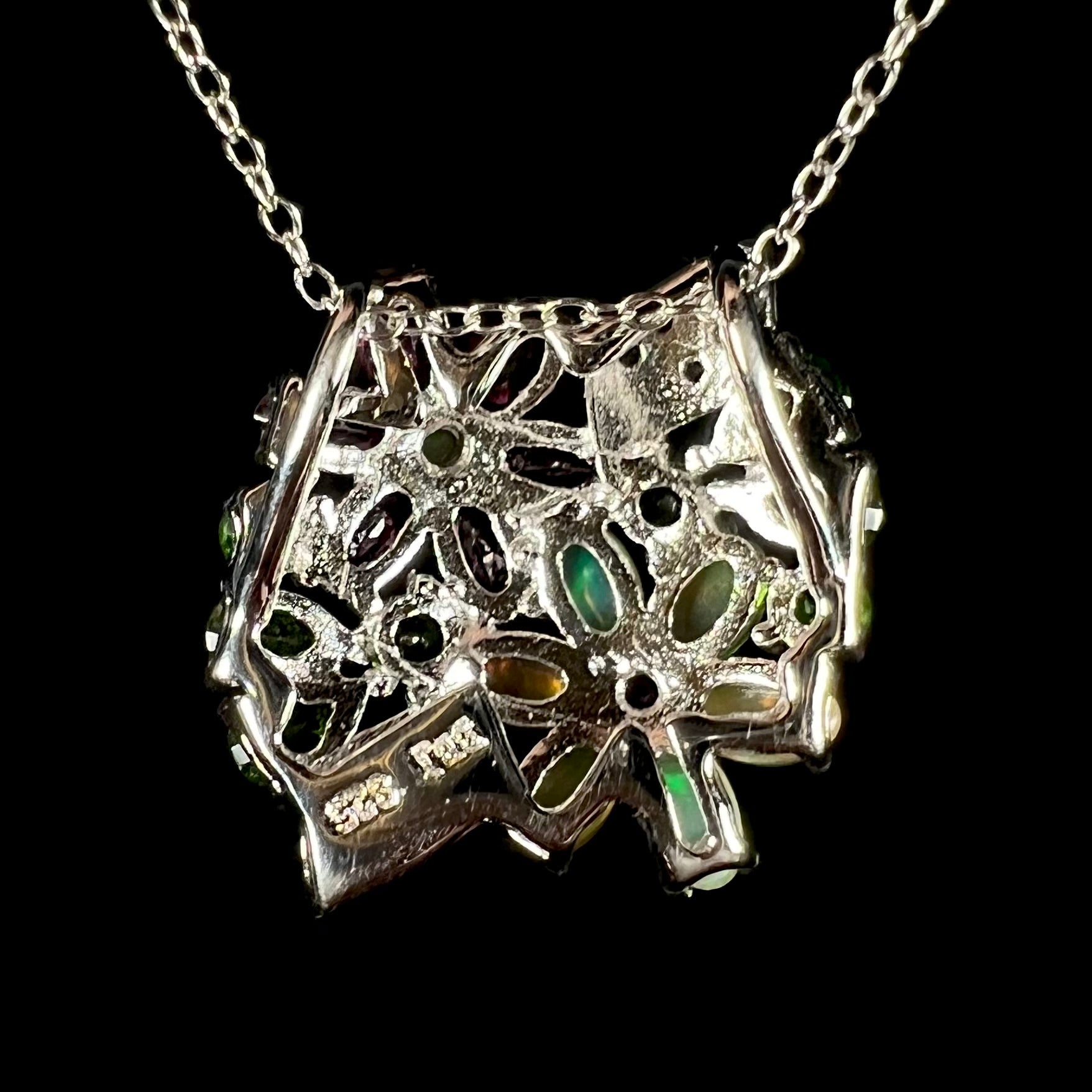 Back side of a silver multi-gemstone cluster flower necklace.  The pendant has a slide bail.