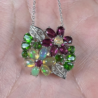 A sterling silver gemstone flower necklace shown close-up in the palm of a hand.