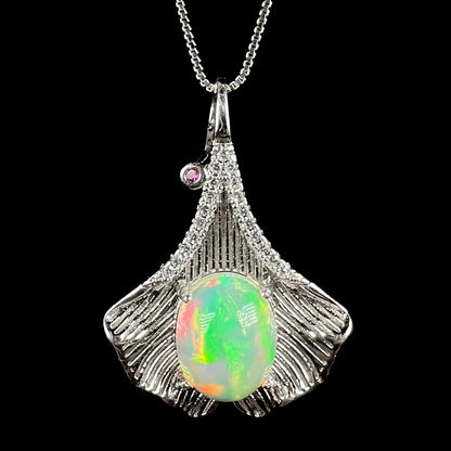 Close-up of women's sterling silver Ethiopian opal and pink sapphire pendant with ginko leaf design on chain