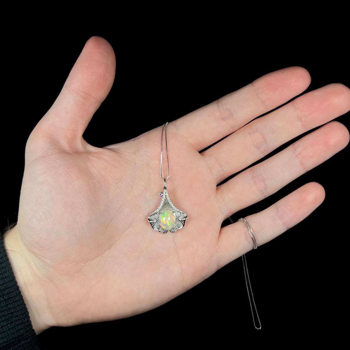 Hand holding sterling silver Ethiopian opal ginko leaf necklace
