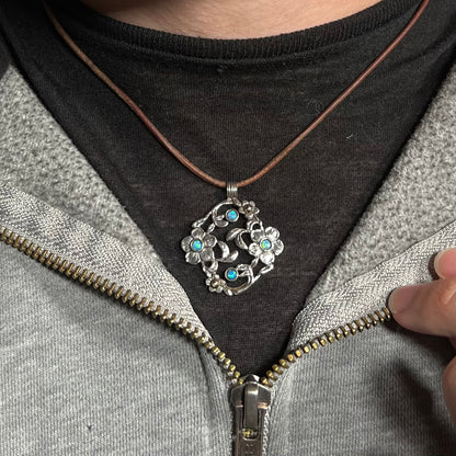 A two-tone sterling silver and 14k gold opal dogwood flower necklace worn around a neck against a dark shirt.