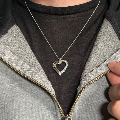 A two-tone sterling silver and yellow gold lab-created opal and CZ heart necklace, worn around a neck.