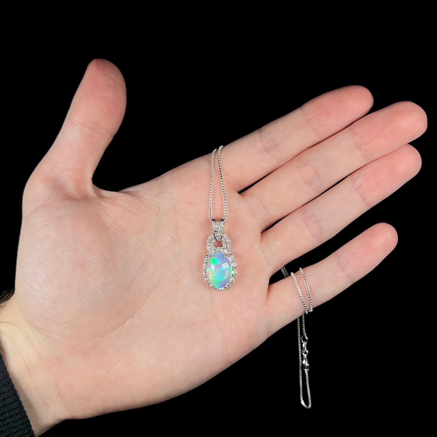 Hand holding sterling silver jelly opal necklace with box-style chain in hand