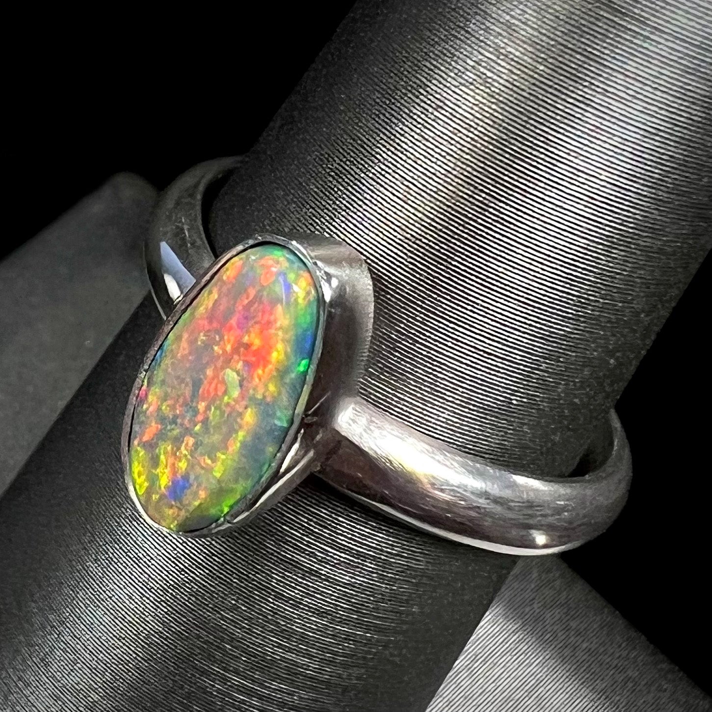 Angled top-view of a sterling silver Lightning Ridge opal ring with a vibrant red and orange flash of color.