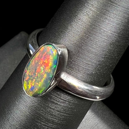 Angled top-view of a sterling silver Lightning Ridge opal ring with a vibrant red and orange flash of color.