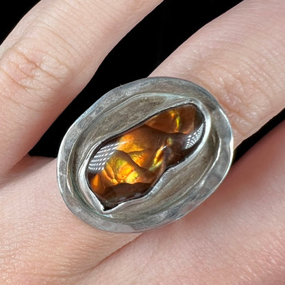 Close-up of a handmade sterling silver Mexican fire agate ring, worn on a finger.